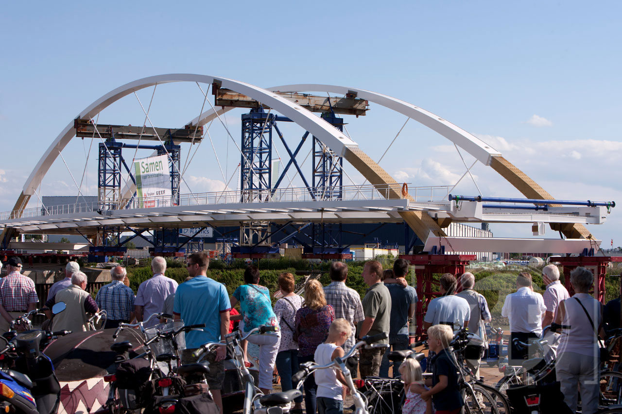 Donderdag stonden honderden mensen op de Loskade in Zutphen om de start van het transport van de nieuwe brug over het Twentekanaal bij Eefde te bekijken. De 117 meter lange brug werd vanaf de kade met grote precisie op een ponton geplaatst waarmee het zaterdagmorgen in alle vroegte over de IJssel naar het Twentekanaal zal worden gevaren.