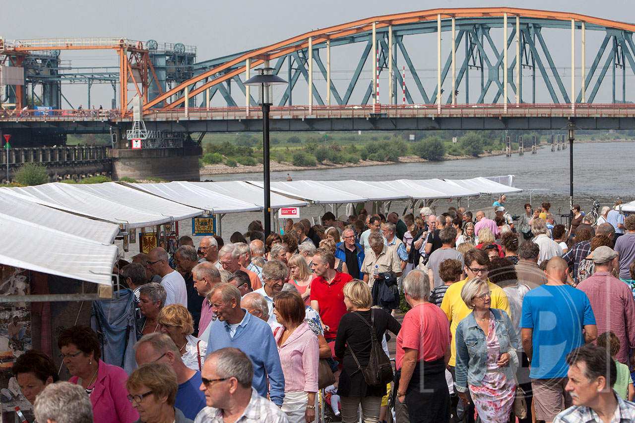 Kunstmarkt langs de IJssel, bezoekers lopen langs de kramen.