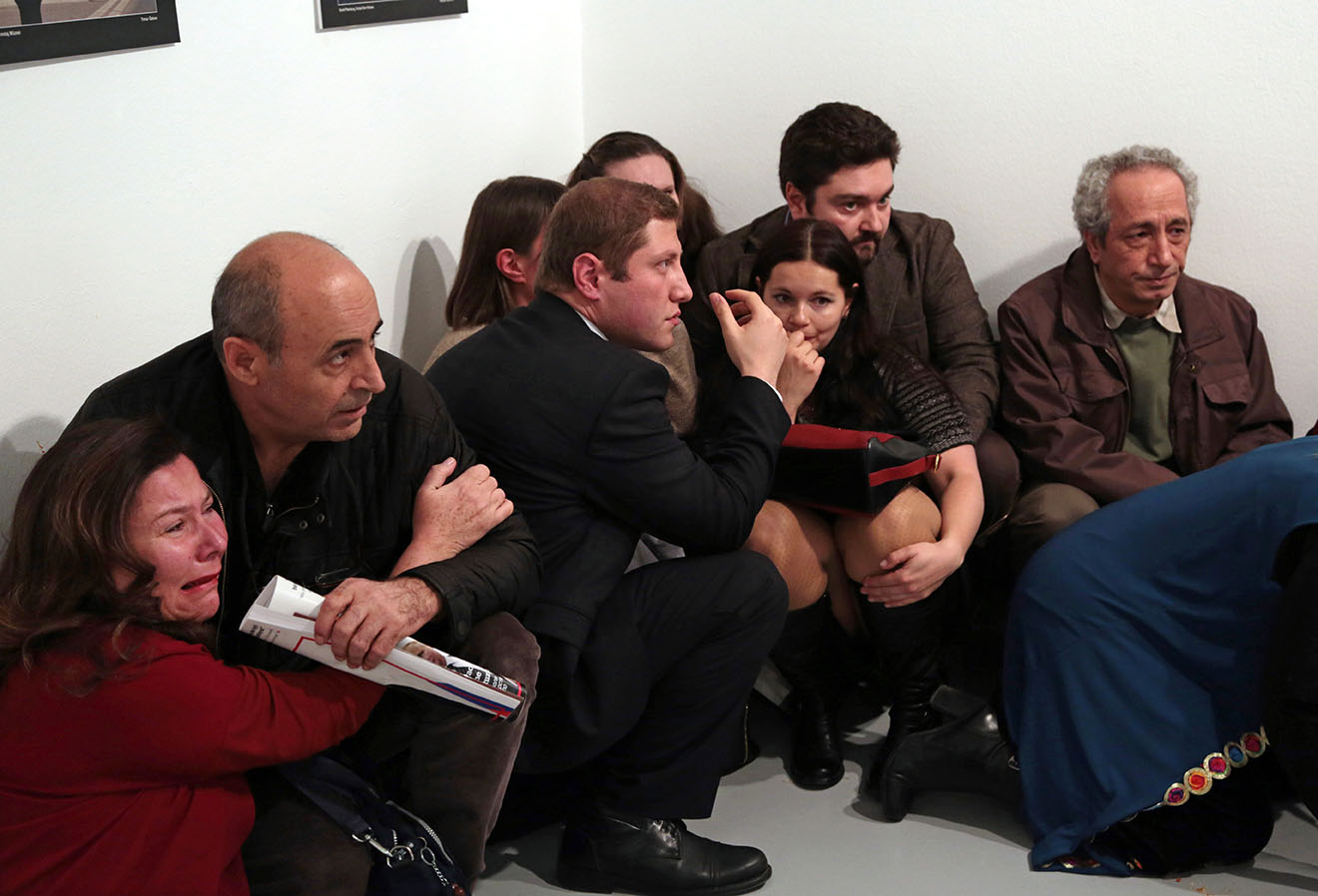 Gallery goers cower after Mevlut Mert Altintas shot Andrei Karlov, the Russian ambassador to Turkey, at an art gallery in Ankara, Turkey, Monday, Dec. 19, 2016. At first, AP photographer Burhan Ozbilici thought it was a theatrical stunt when a man in a dark suit and tie pulled out a gun during the photography exhibition. The man then opened fire, killing Karlov. (AP Photo/Burhan Ozbilici)